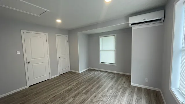 an empty room with wooden floor and windows