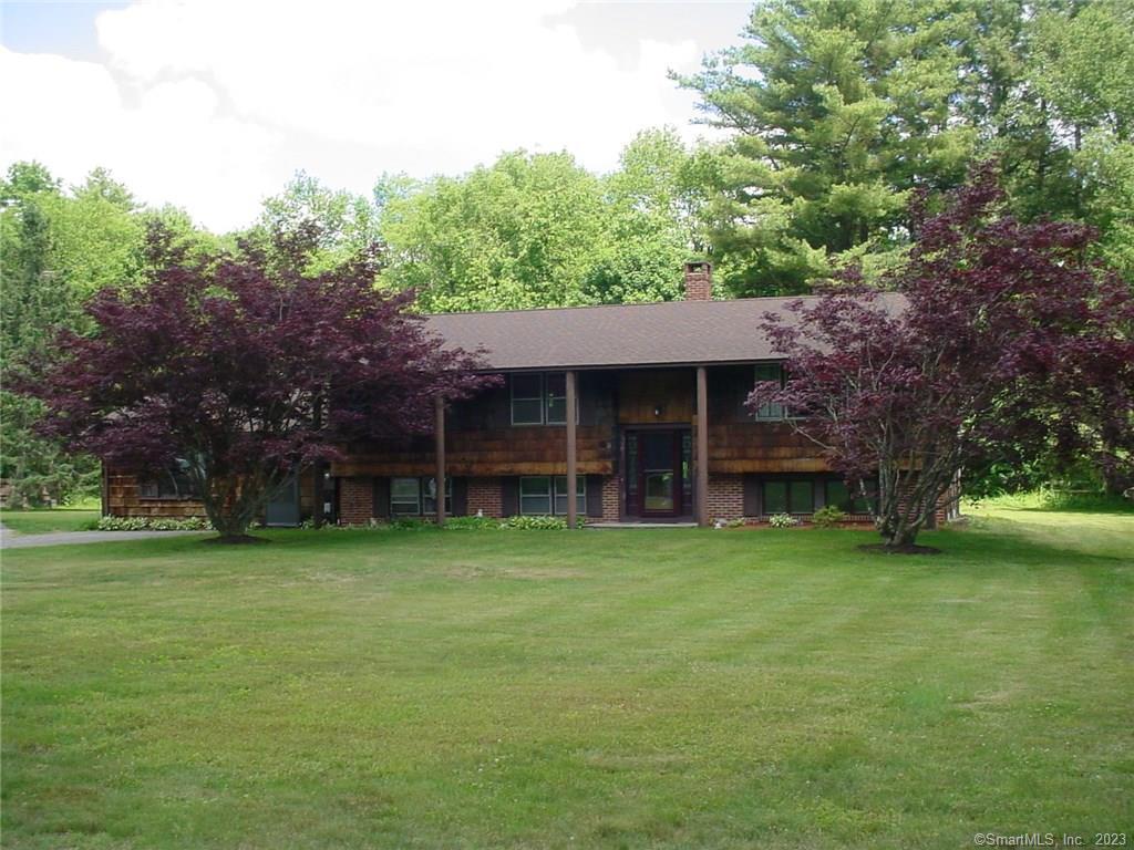 Front of home with beautiful maple trees and lovely plantings.