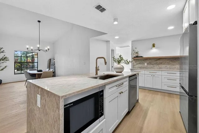 a kitchen with stainless steel appliances granite countertop a sink a stove and a refrigerator