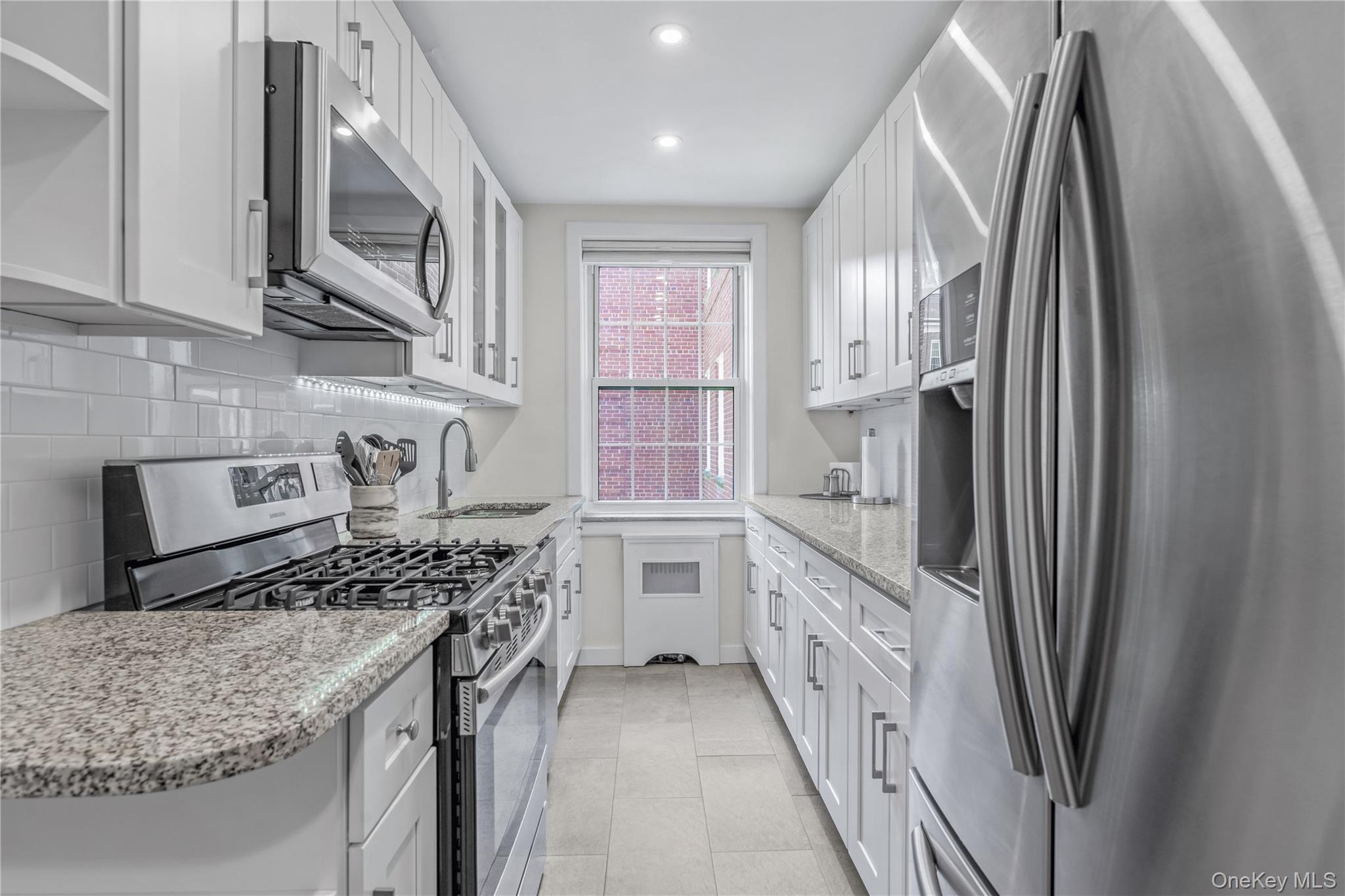 90 Knightsbridge Road, Unit 3N Great Neck, NY 11021 - Photo 7 of 16 a kitchen with stainless steel appliances granite countertop a refrigerator a stove and a sink