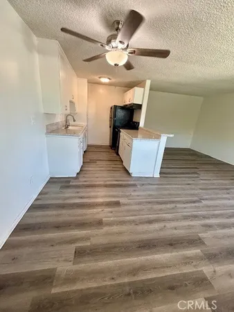 a view of kitchen and empty room with wooden floor
