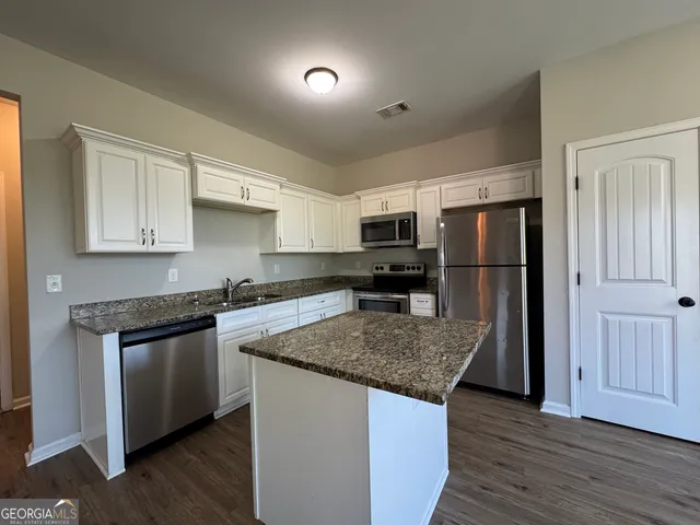 a kitchen with refrigerator cabinets and wooden floor
