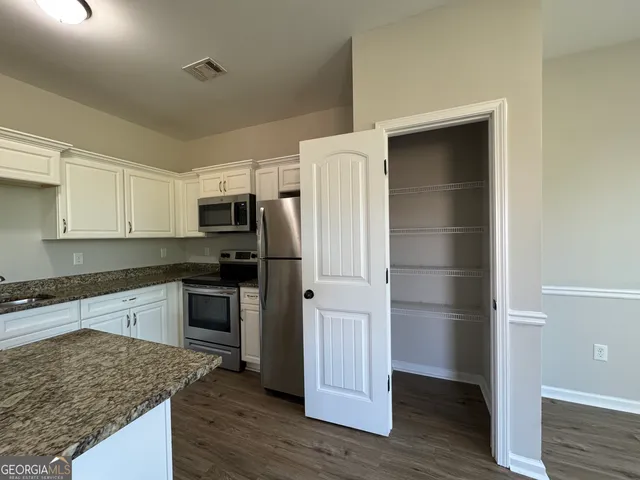 a kitchen with stainless steel appliances granite countertop a sink stove refrigerator and cabinets