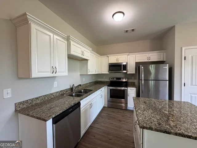 a kitchen with granite countertop wooden floors appliances and sink