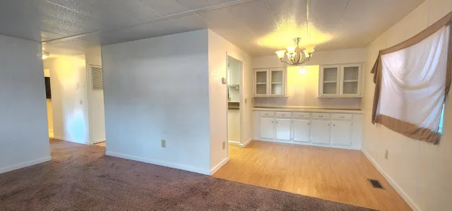 a view of a hallway with wooden floor and chandelier