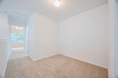 an empty room with windows and chandelier fan