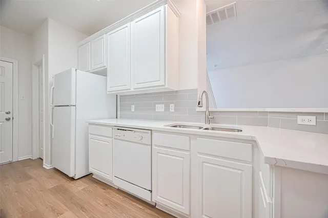 a kitchen with white cabinets and sink