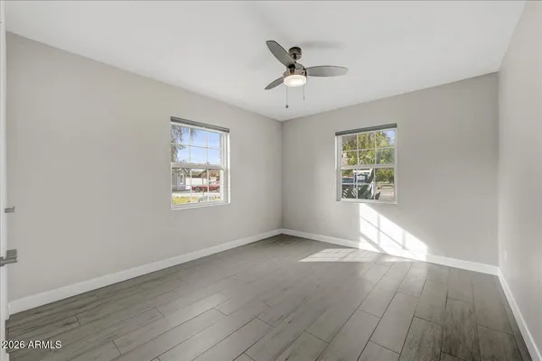 an empty room with wooden floor chandelier fan and windows