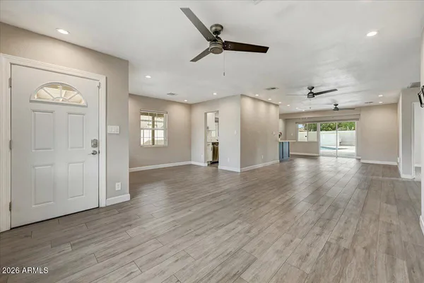 an empty room with wooden floor and a ceiling fan
