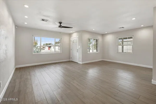 an empty room with wooden floor and windows