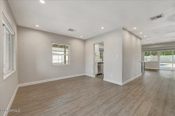 a view of an empty room with wooden floor and a window