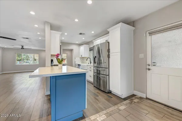 a kitchen with stainless steel appliances kitchen island granite countertop a refrigerator a sink and a oven