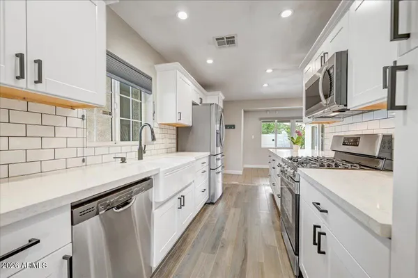 a kitchen with a sink stove cabinets and wooden floor