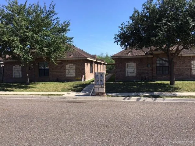 a view of the house with a yard and large tree
