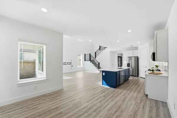 a large living room with stainless steel appliances kitchen island granite countertop wooden floor and a window