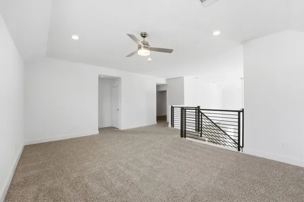 an empty room with ceiling fan and windows