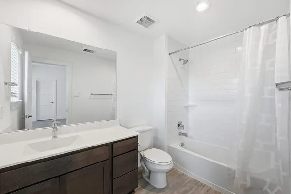 a bathroom with a double vanity sink toilet mirror and bathtub
