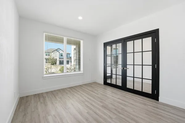 an empty room with wooden floor and windows