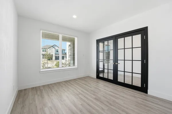 an empty room with wooden floor and windows