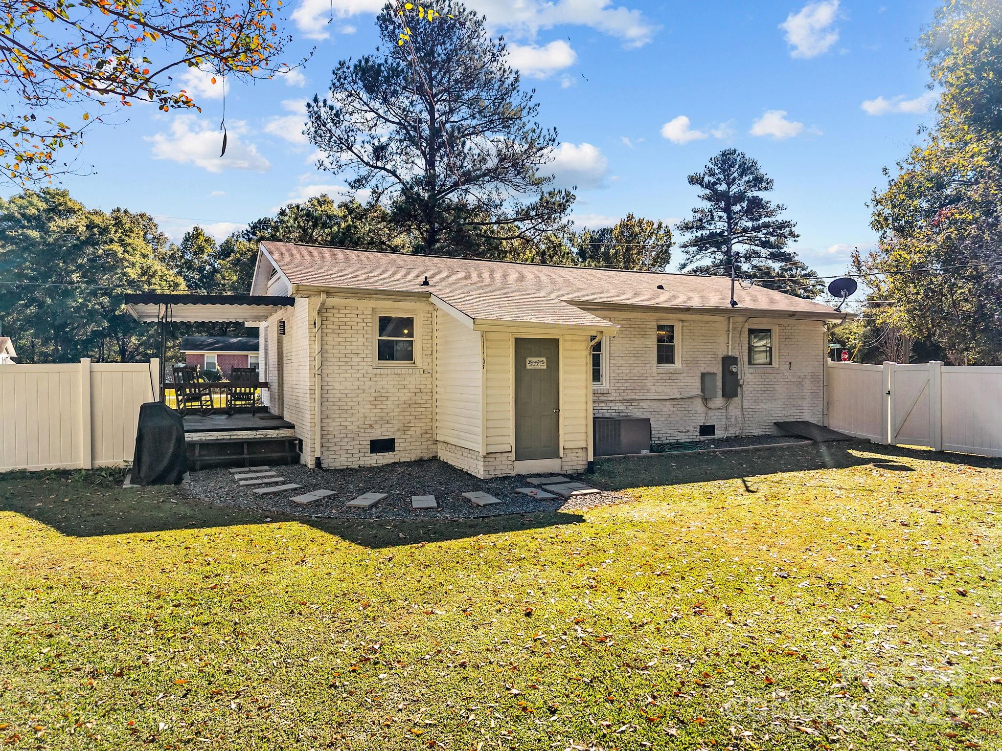 976 10 Oaks Drive Lancaster, SC 29720 - Photo 18 of 24 a view of a white house with swimming pool lawn chairs and wooden fence