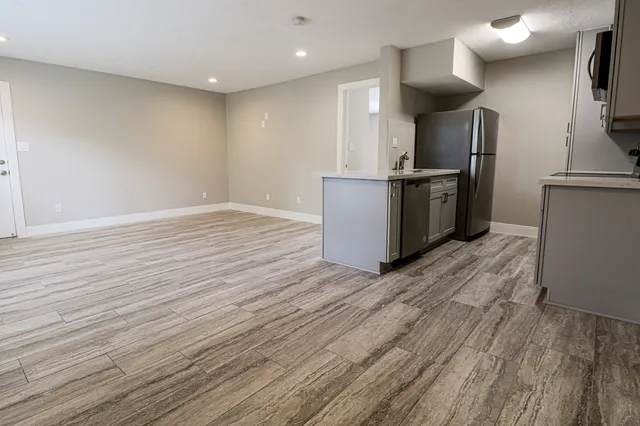 a kitchen with stainless steel appliances a refrigerator and a wooden floor
