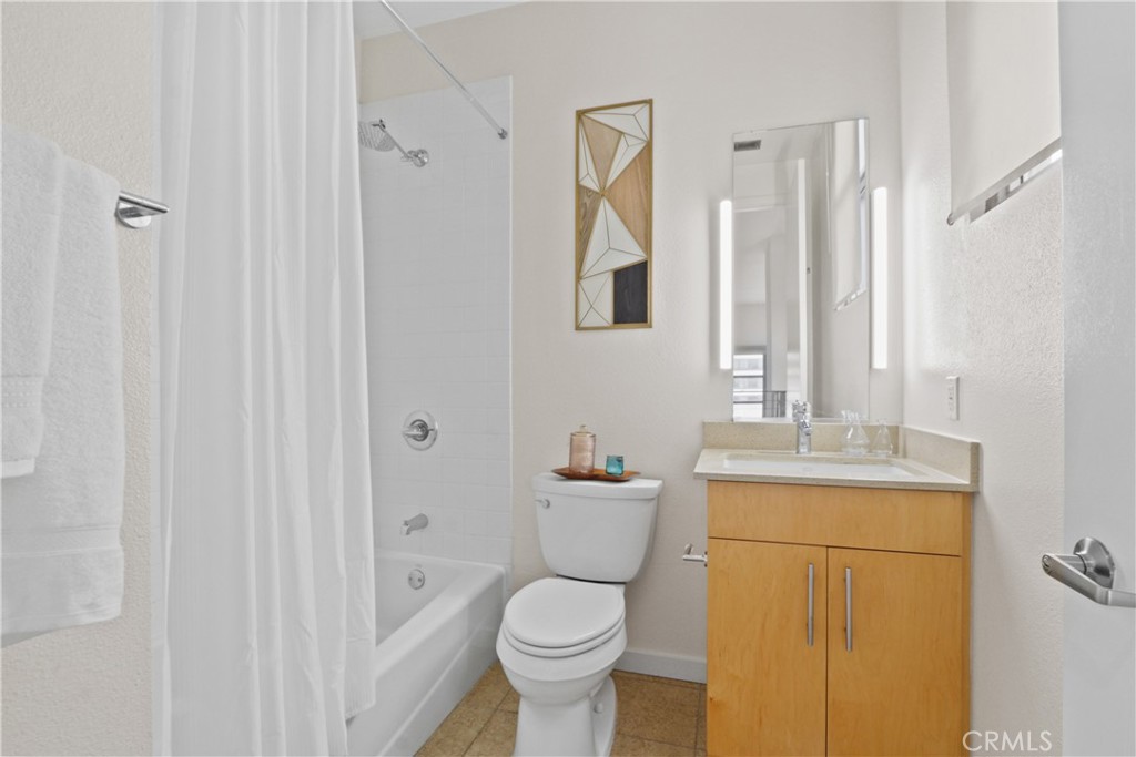 133 The Promenade North, Unit 402 Long Beach, CA 90802 - Photo 10 of 26 a bathroom with a granite countertop toilet a sink and a mirror
