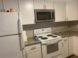 a kitchen with granite countertop white cabinets and white stainless steel appliances