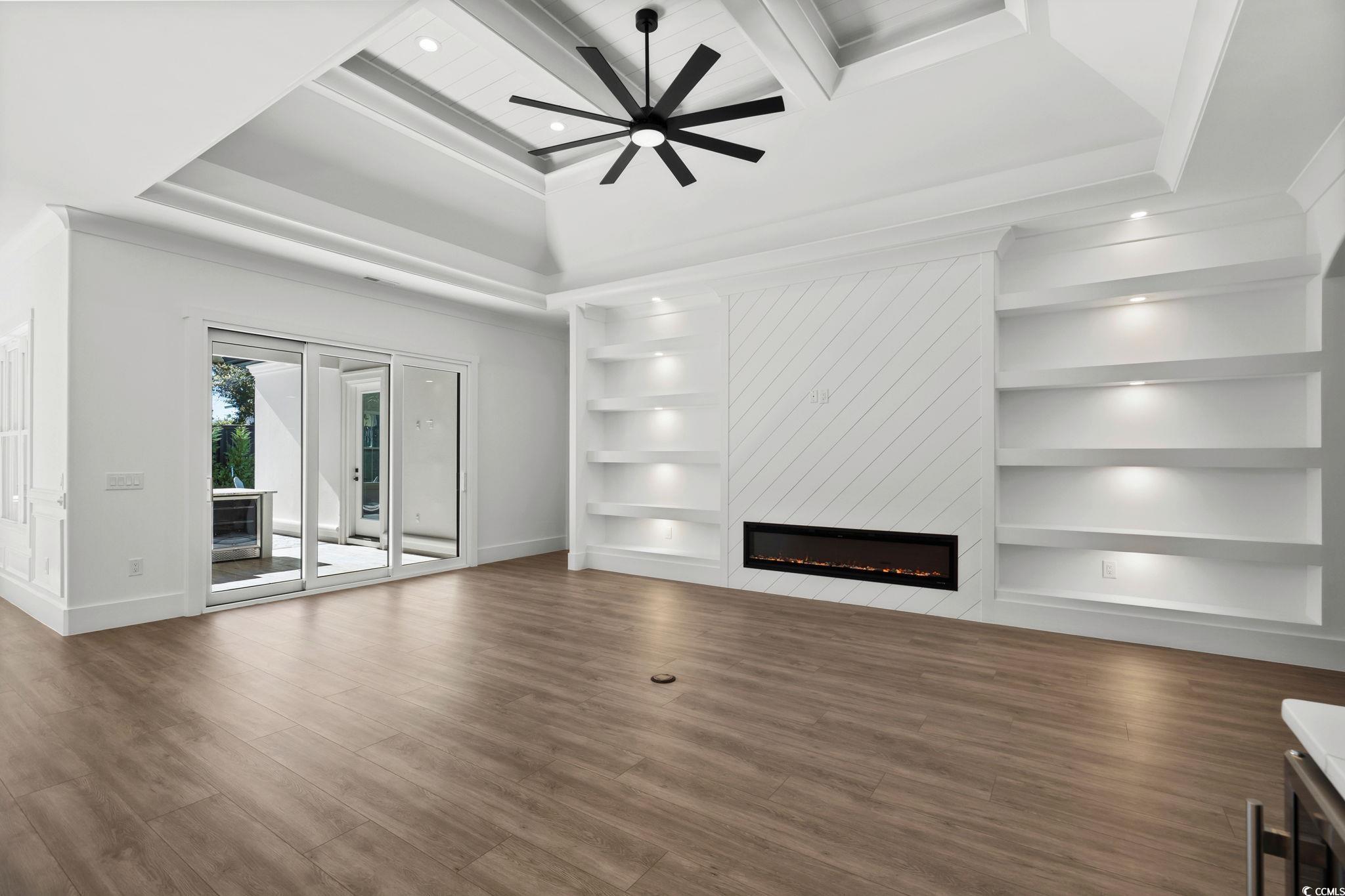 311 73rd Avenue North Myrtle Beach, SC 29572 - Photo 12 of 40 Unfurnished living room with a large fireplace, wood finished floors, a ceiling fan, beamed ceiling, and coffered ceiling