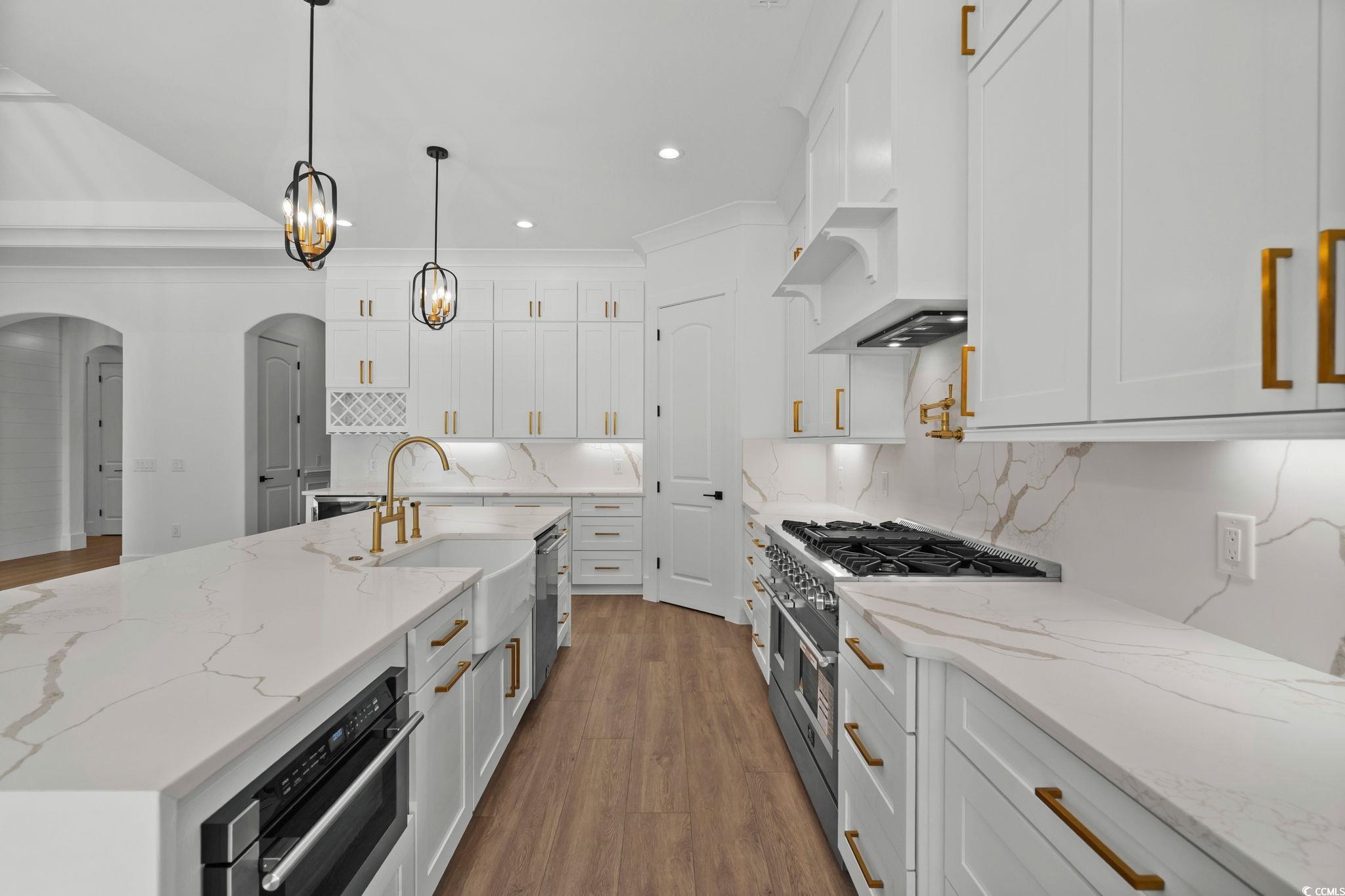 311 73rd Avenue North Myrtle Beach, SC 29572 - Photo 15 of 40 Kitchen with arched walkways, light stone counters, dark wood finished floors, white cabinetry, and recessed lighting