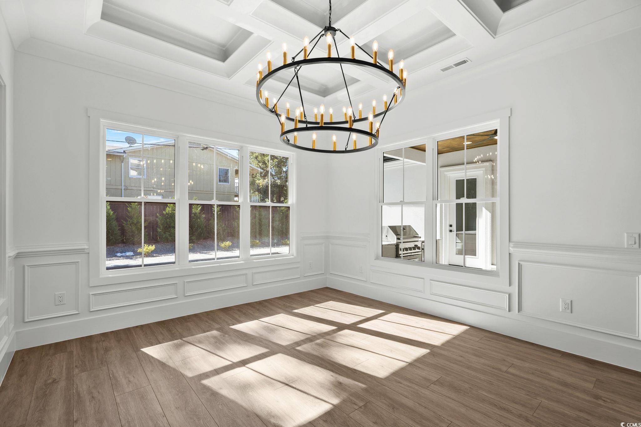 311 73rd Avenue North Myrtle Beach, SC 29572 - Photo 18 of 40 Unfurnished dining area with wood finished floors, a decorative wall, a wainscoted wall, a chandelier, and beamed ceiling