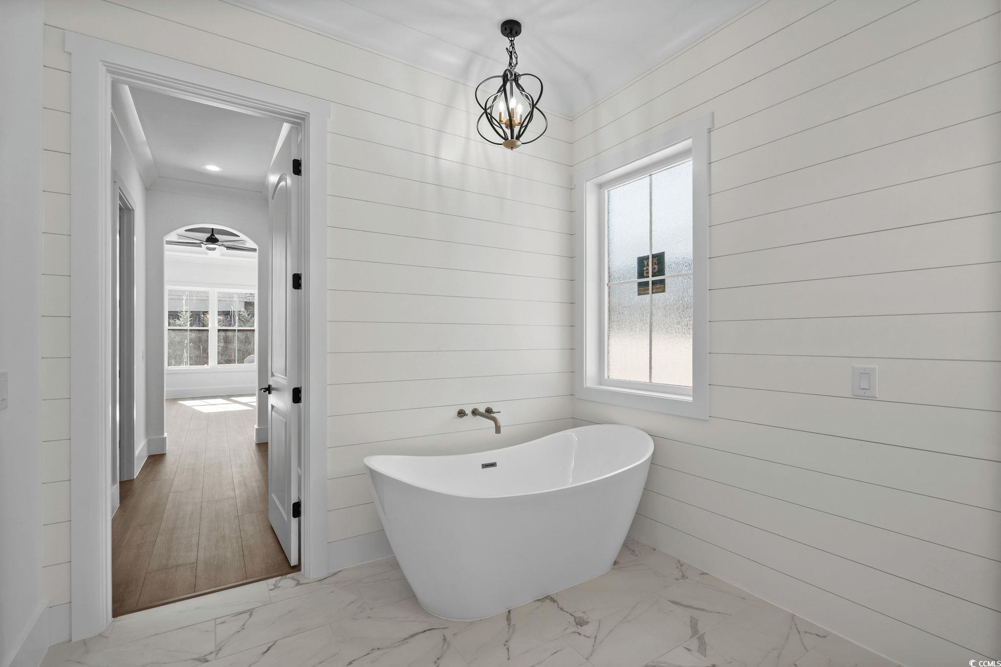 311 73rd Avenue North Myrtle Beach, SC 29572 - Photo 23 of 40 Full bath featuring a freestanding tub, light marble finish floors, crown molding, a chandelier, and wooden walls