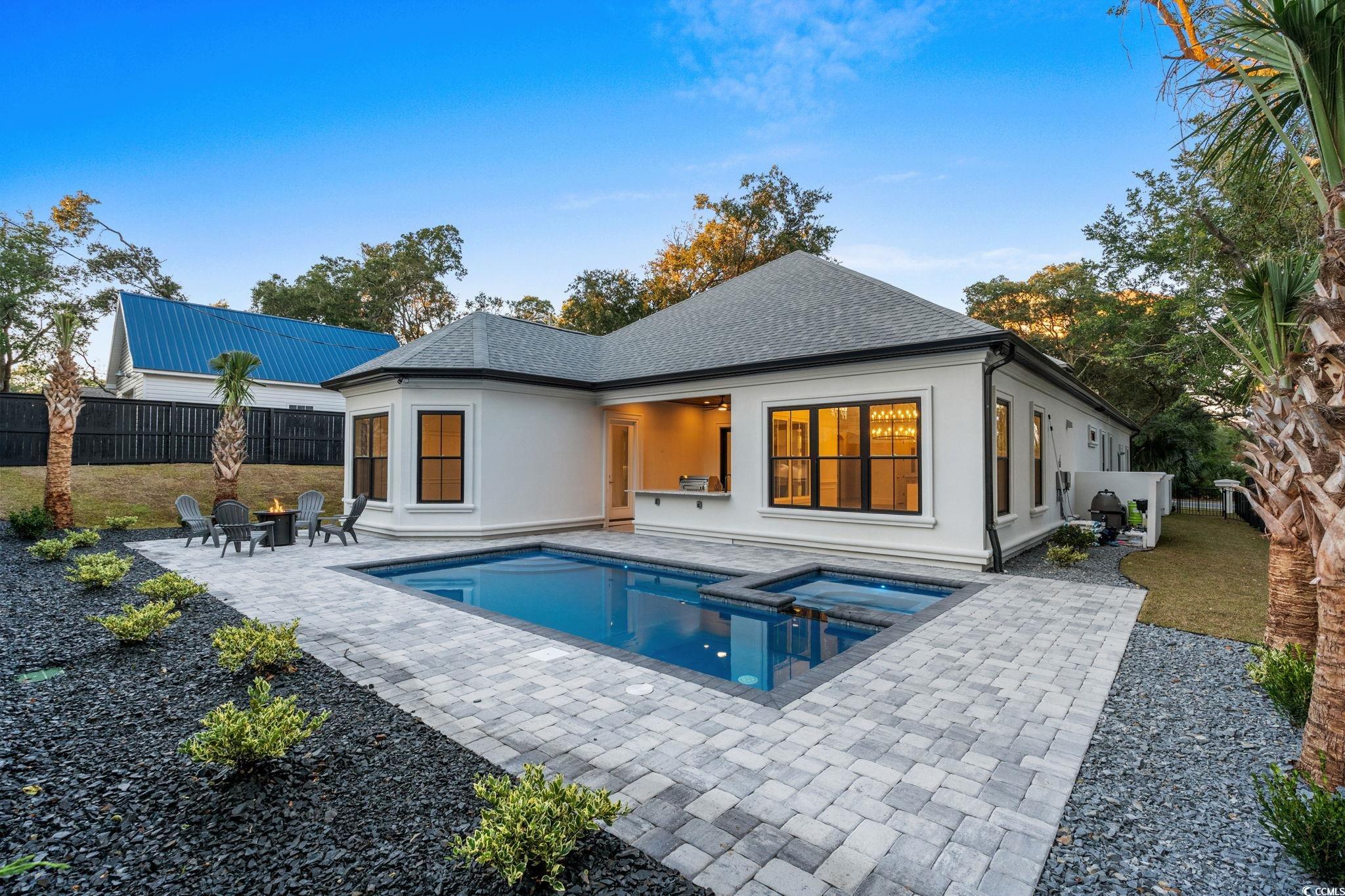 311 73rd Avenue North Myrtle Beach, SC 29572 - Photo 30 of 40 Back of house featuring a fenced backyard, a patio area, roof with shingles, a pool with connected hot tub, and stucco siding