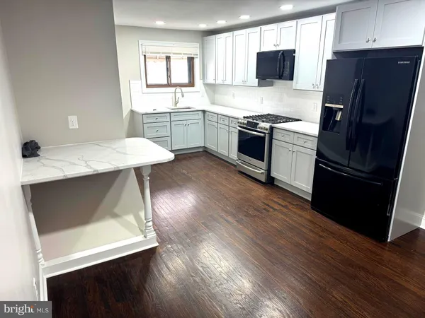 a kitchen with stainless steel appliances granite countertop a sink stove refrigerator and wooden floor
