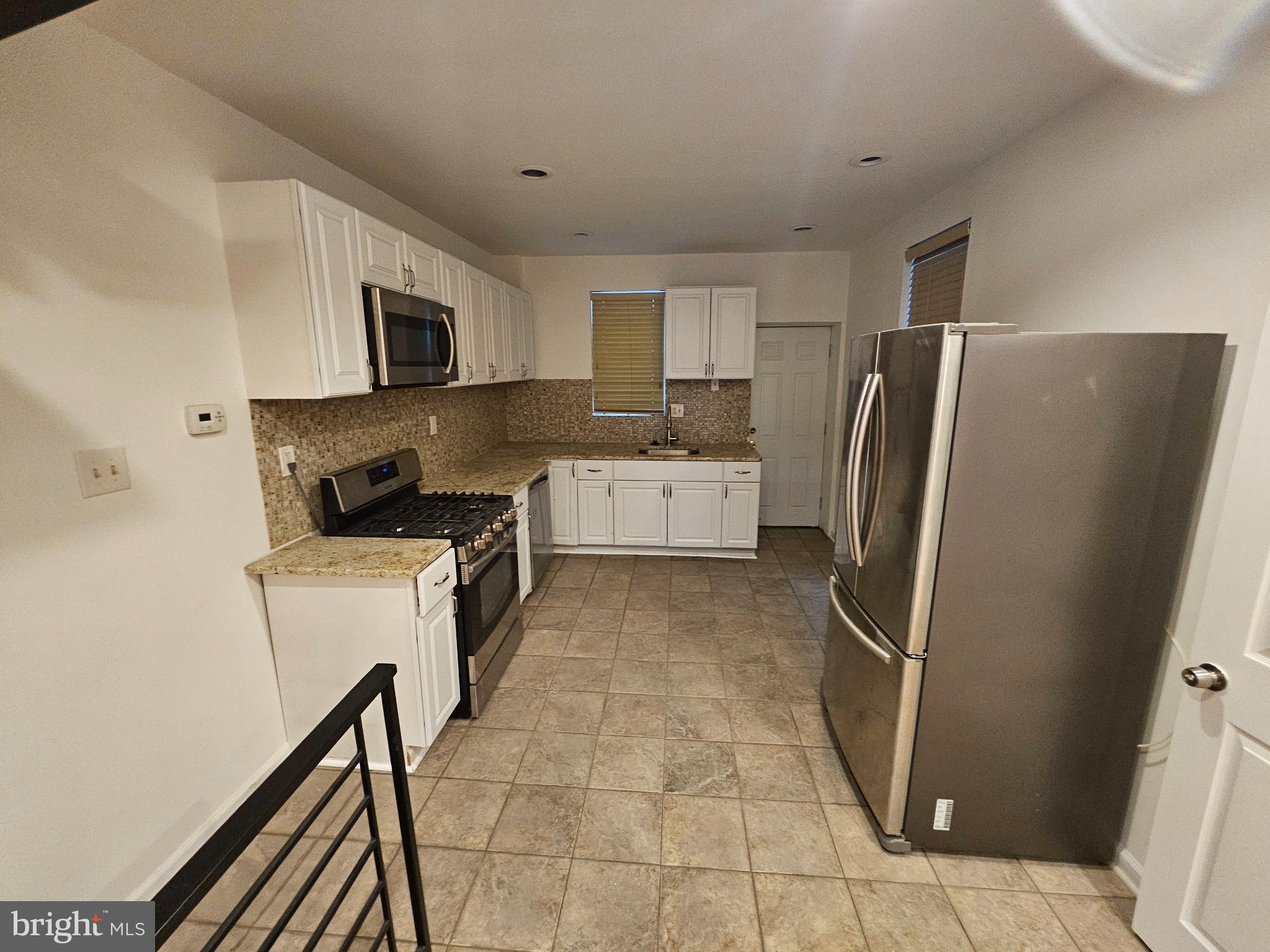 3025 Redner Street Philadelphia, PA 19121 - Photo 3 of 15 a kitchen with a refrigerator a stove top oven and white cabinets