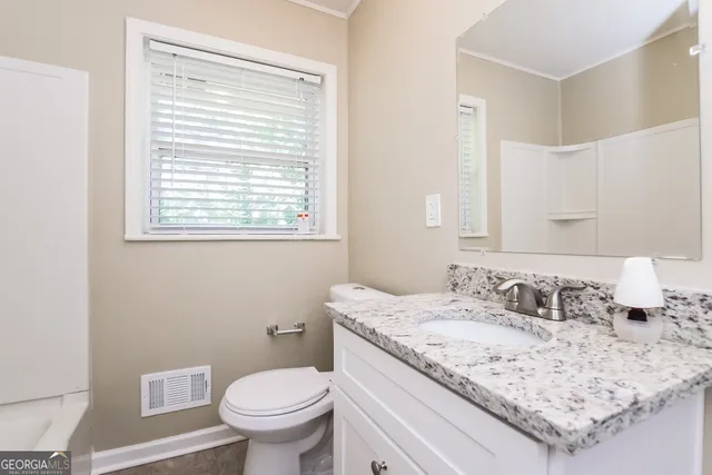 a bathroom with a granite countertop sink toilet and mirror
