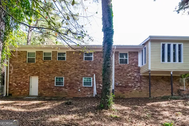 a brick house that has a small yard and large trees