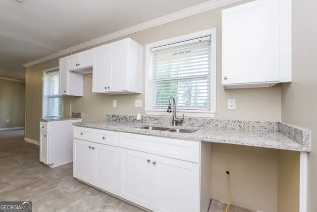 a kitchen with granite countertop kitchen island with white cabinets and a window