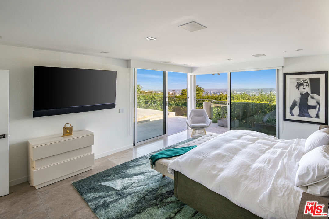 1476 Carla Ridge Beverly Hills, CA 90210 - Photo 22 of 27 a living room with a flat screen tv and a floor to ceiling window