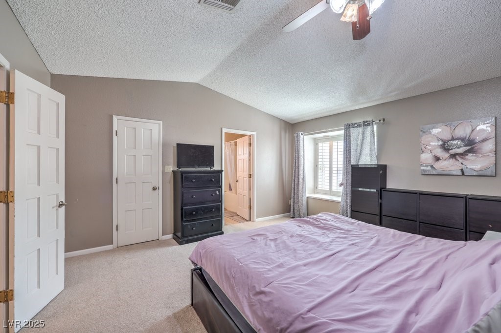2240 Grayson Circle Henderson, NV 89014 - Photo 18 of 38 Bedroom featuring lofted ceiling, light carpet, connected bathroom, a ceiling fan, and a textured ceiling
