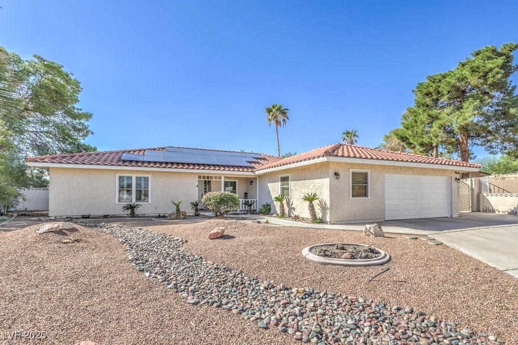 2240 Grayson Circle Henderson, NV 89014 - Photo 2 of 38 View of front of house featuring stucco siding, concrete driveway, a garage, and roof mounted solar panels