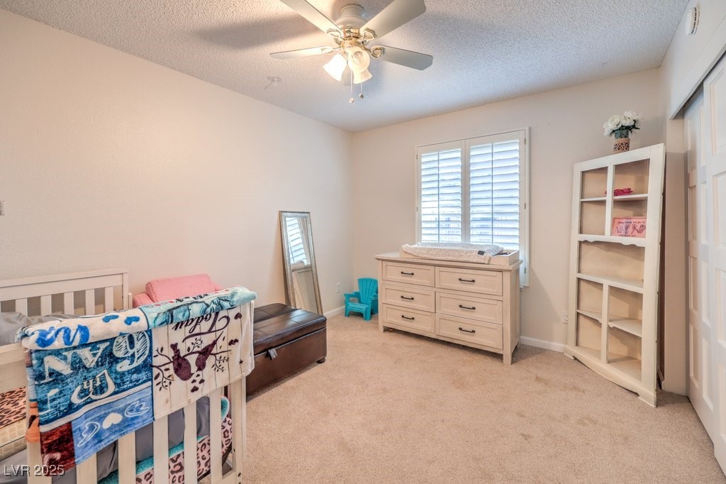 2240 Grayson Circle Henderson, NV 89014 - Photo 24 of 38 Bedroom with light carpet, multiple windows, ceiling fan, and a textured ceiling