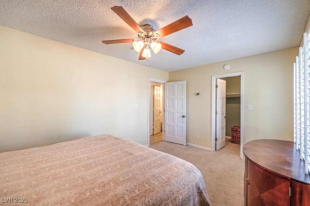 2240 Grayson Circle Henderson, NV 89014 - Photo 28 of 38 Bedroom featuring light colored carpet, a spacious closet, a textured ceiling, and a ceiling fan