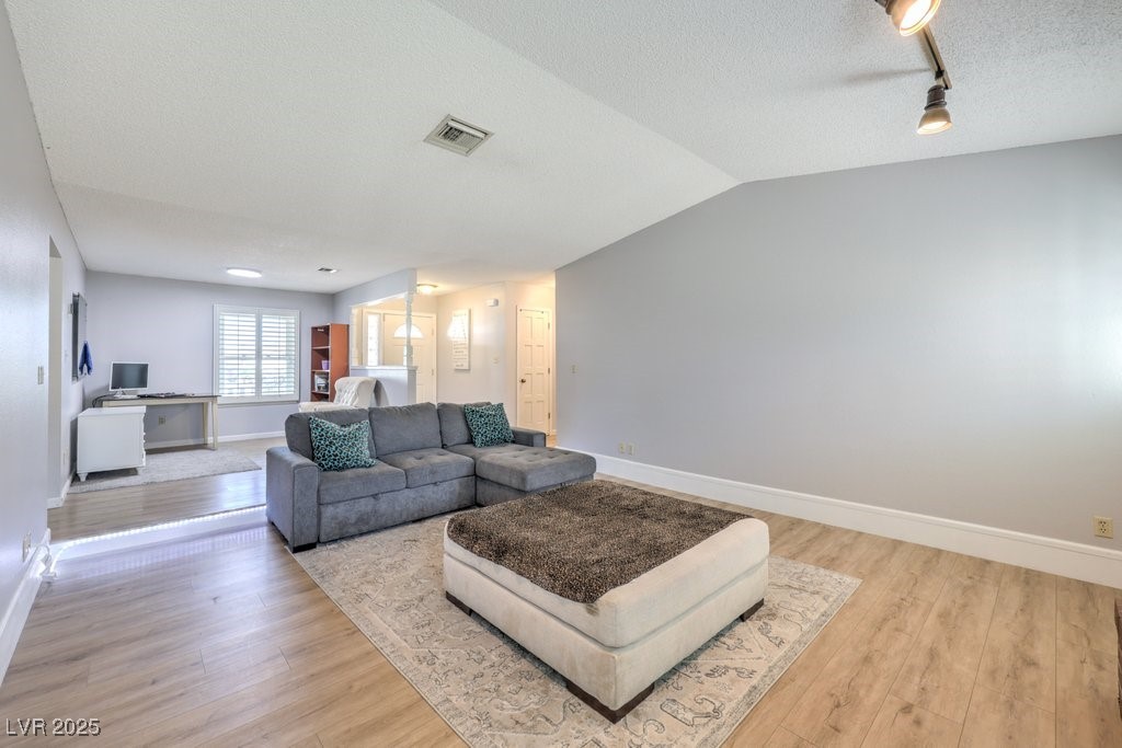 2240 Grayson Circle Henderson, NV 89014 - Photo 7 of 38 Living area featuring a textured ceiling, rail lighting, an office area, light wood-style floors, and lofted ceiling
