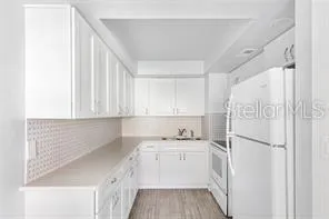 a kitchen with a sink a refrigerator a stove and white cabinets