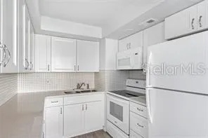 a kitchen with granite countertop white cabinets and white appliances