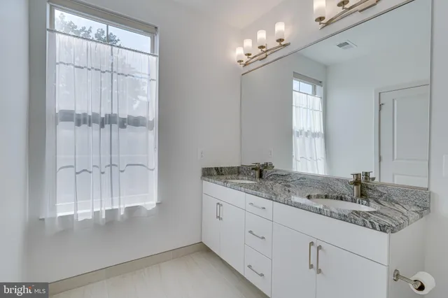 a bathroom with a granite countertop sink a mirror and a shower