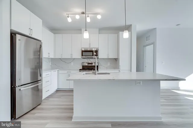 a kitchen with kitchen island white cabinets and stainless steel appliances