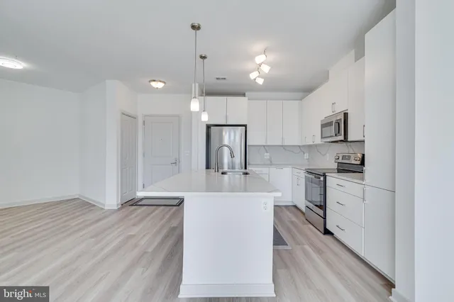 a large kitchen with kitchen island a sink stainless steel appliances and white cabinets