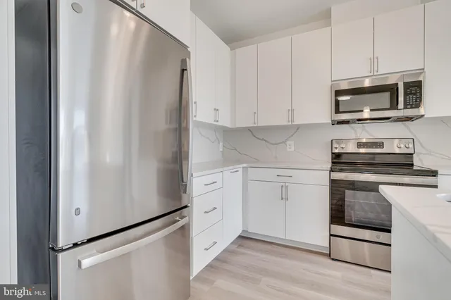 a kitchen with stainless steel appliances white cabinets and a refrigerator