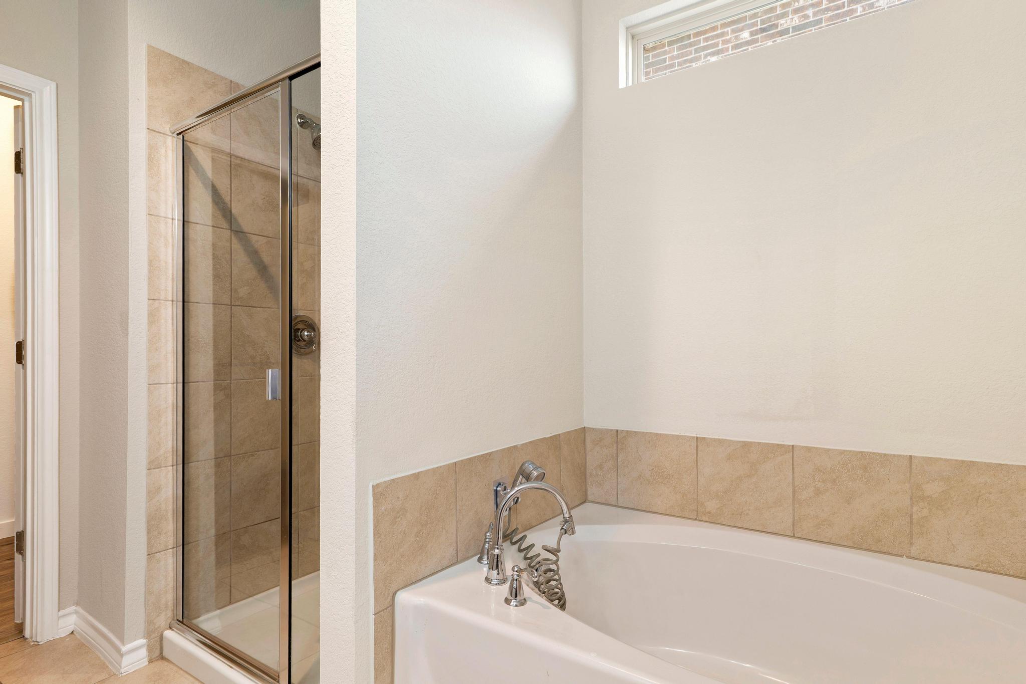 1341 Eagle Ray Street Leander, TX 78641 - Photo 18 of 37 A well-appointed bath features a deep soaking tub and a tiled shower with glass enclosure.